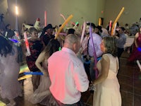 a group of people dancing with lightsabers at a party