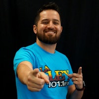 a man wearing a blue t - shirt pointing to the camera